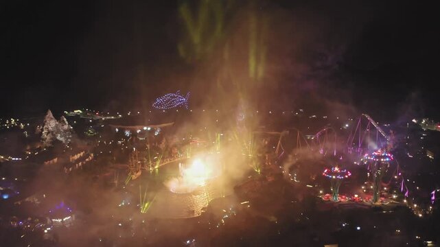 Aerial Night View of Illuminated Theme Park with Fireworks and Light Beams