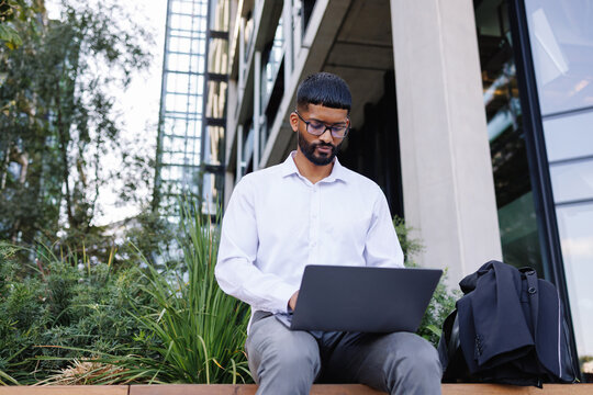 Young businessman working remotely on laptop in city