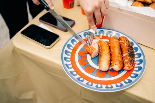 People Enjoy Grilled Sausages at a Gathering in a Home Setting