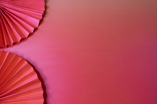 Minimalist composition with two red paper fans on a monochromatic background with plenty of space for text