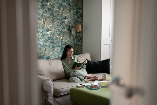 Asian woman reading book in living room at home