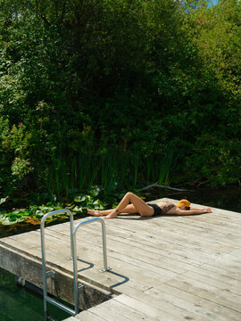 Woman sunbathes on a swimming dock on Vancouver island