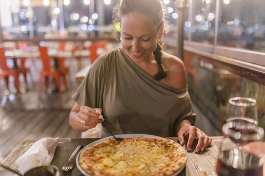 Woman eating pizza while having dinner at restaurant