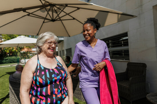 Caregiver assisting senior woman to swimming pool