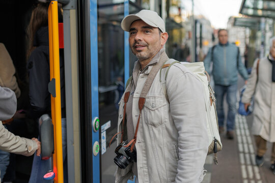 Smiling man with camera boarding a city bus