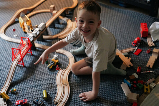 Boy Smiling While Playing with a Toy Train Set