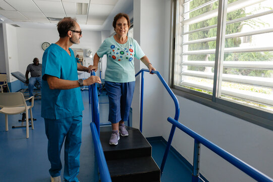 Elderly woman walking up therapy steps with physical therapist
