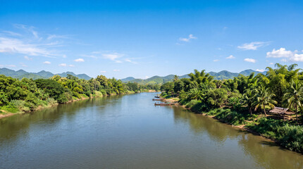 Fototapeta premium Serene river landscape peaceful K with calm water lush riverbanks palm trees distant hills clear sky evoking tranquility