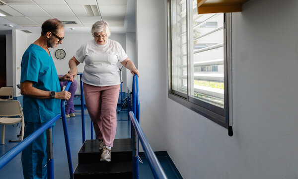 Senior woman doing physical therapy walking downstairs with therapist