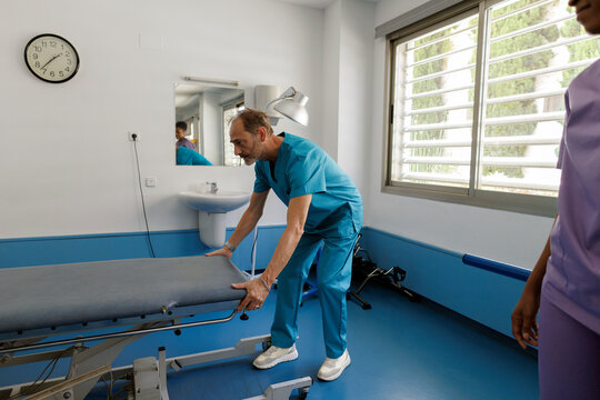 Healthcare worker preparing examination table in medical room