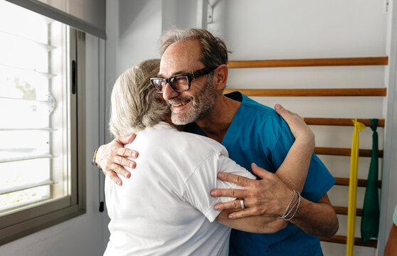 Physiotherapist embracing senior woman providing comforting support