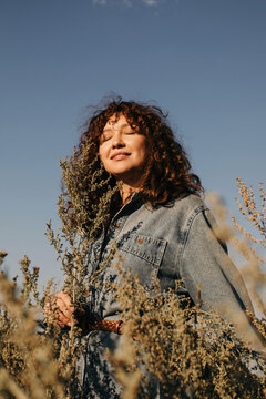 Curly happy woman in denim against blue sky