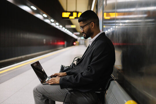 Young businessman working on laptop at subway station