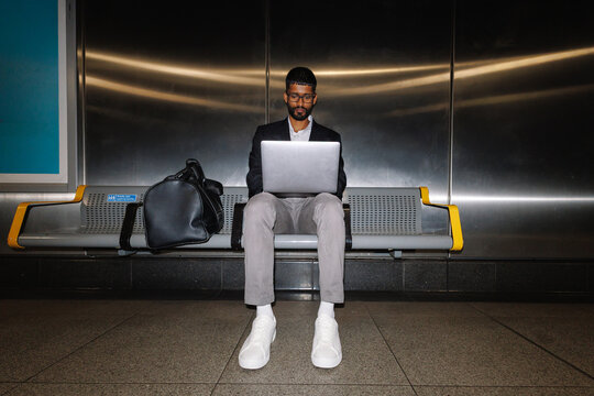 Young businessman working remotely waiting at subway station