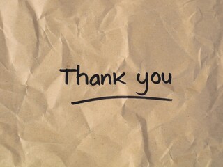 Handwritten Thank you text with an underline on a crumpled brown craft paper background. Features a rustic, vintage texture ideal for appreciation, gratitude, and eco-friendly greeting concepts © Eka