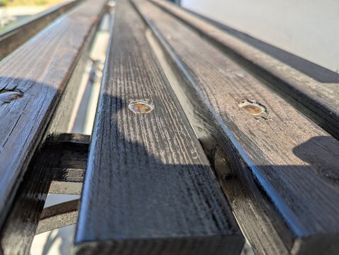 Sunlight hits the metallic screws and rustic grain of a weathered
