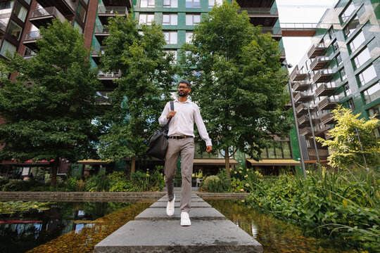 Young businessman walking on stepping stones in urban park