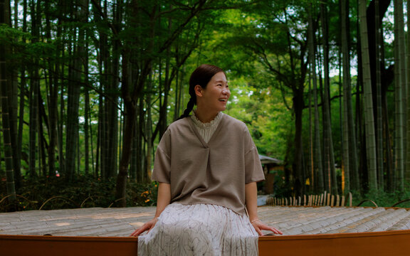 Joyful Woman Sitting in a Japanese Bamboo Garden