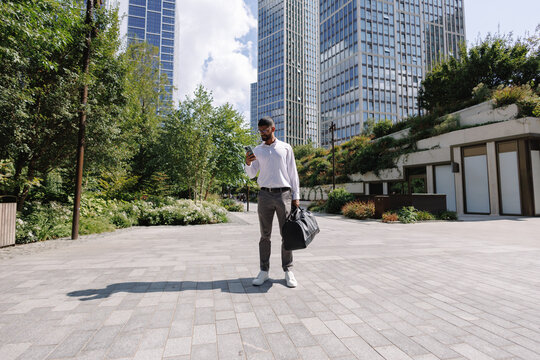 Young businessman using smartphone in modern city park