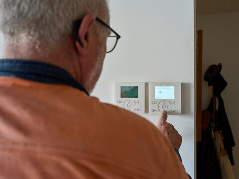 Serviceman Adjusts a Temperature Control Panel in a Home