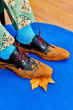 a dry autumn leaf caught beneath the muddy shoe of a seated man