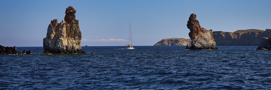 Bear Rocks, A sailboat navigates between distinctive rock formations in the open sea, Koudes, volcanic island, island, Milos, Cyclades, Greek Islands, Greece