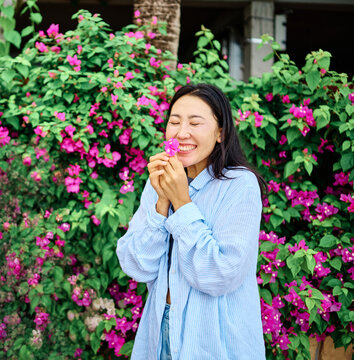 Smiling young woman laughing in a candid seaside portrait, enjoying the ocean breeze and bright daylight. Casual button-up shirt, relaxed posture and genuine joy create a carefree, positive lifestyle 