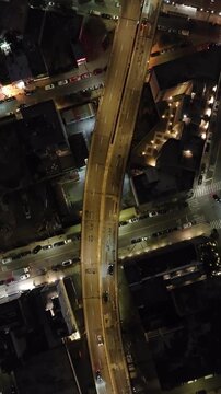Vertical video: Aerial views capture glowing streets and buildings in New York City at night. Cars traverse busy roads, emphasizing the lively urban scene and vibrant city atmosphere