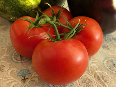 Bright red tomatoes with vibrant skin and green stems rest on a
