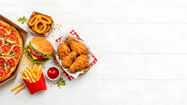 Fast food feast with pizza burger fries chicken on white wooden table