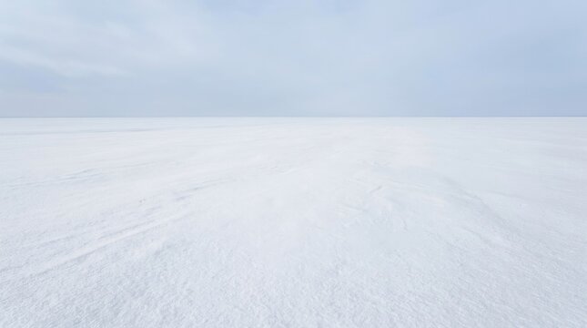 Expansive snow covered field with light clouds in the sky.