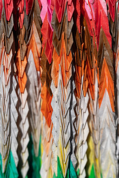 Close up of colorful origami paper cranes connected in rows symbolizing peace and hope in Japanese tradition