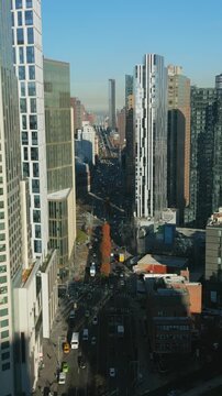 Vertical video: Forwards fly along row of modern high rise business downtown buildings. Sunny day in metropolis. New York City, USA