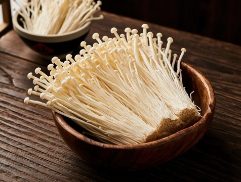 Fresh enoki mushrooms in wooden bowl on dark rustic table. Raw white enoki fungi bundles serve as healthy organic ingredient for japanese cuisine. Close up view of delicate edible mushrooms ready for