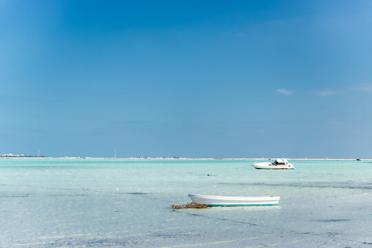 Two fibreglass fishing boats anchored in the shallow turquoise sea near the shore of Purple Island, Al Khor, Qatar