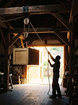 Worker lifting heavy crate with block and tackle pulley, leverage
