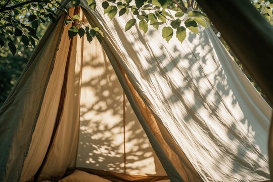 Sunlight filters through green leaves onto canvas tent fabric. Soft shadows create calm mood inside cozy camping shelter. Peaceful outdoor retreat in nature for summer travel. Relaxing wilderness