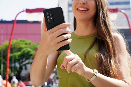 Unidentified smiling woman using mobile phone in Liberdade neighborhood of Sao Paulo, Brazil