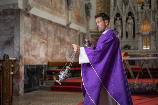 A parish priest holds a censer while leading worship during holy mass in a Catholic church.