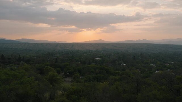 Golden dusk light spilling over distant hills and forest canopy