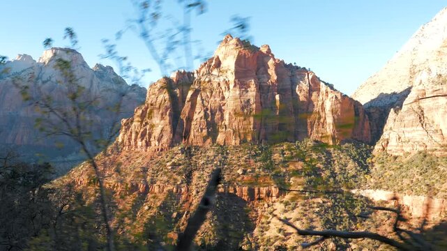 Scenic drive revealing the majestic red rock mountains and canyon cliffs of zion national park in utah, showing the rugged, sunny landscape from a moving vehicle perspective