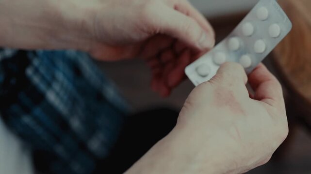 Close up of male hands holding and examining a blister pack of tablets