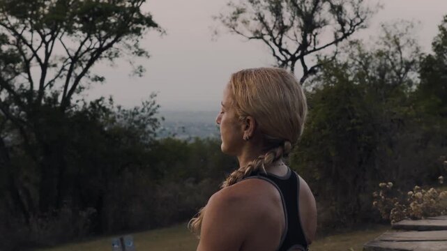 Woman stands in serene stillness as the camera circles over a misty valley view