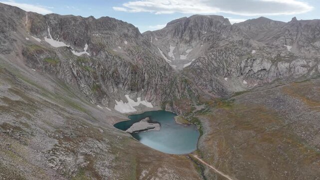 4K Aerial View of a High Mountain Lake Surrounded by Rocky Peaks.