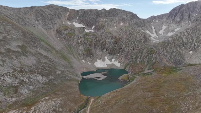 4K Aerial View of a High Mountain Lake Surrounded by Rocky Peaks.