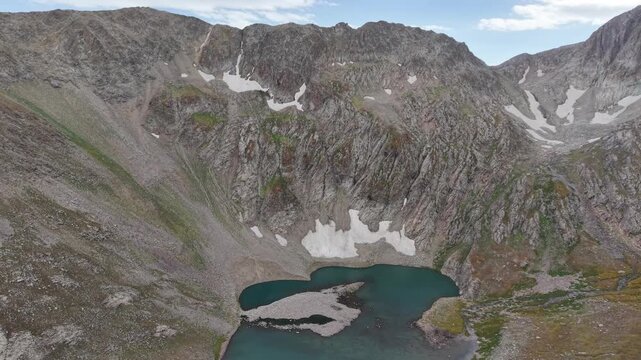 4K Aerial View of a High Mountain Lake Surrounded by Rocky Peaks.