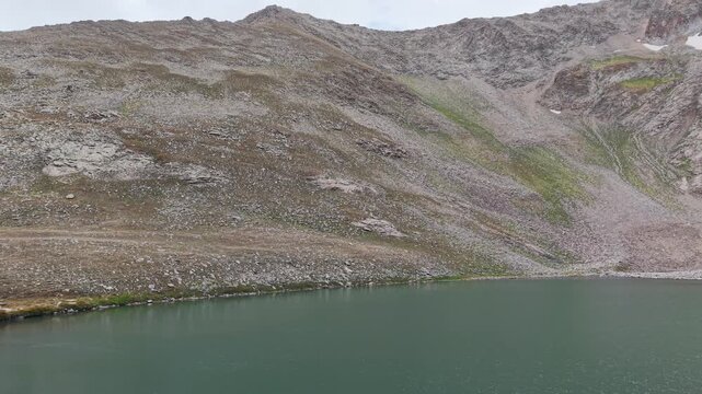 4K Aerial View of a High Mountain Lake Surrounded by Rocky Peaks.