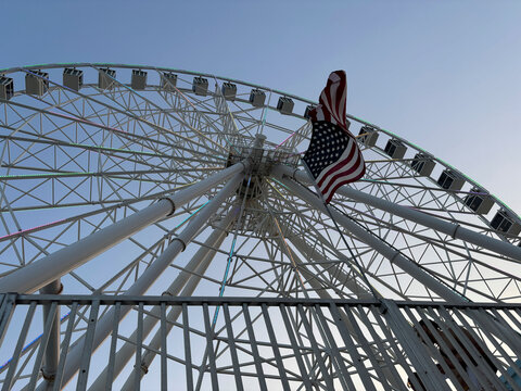 Low angle view of the big wheel of the pier and an American flag, Atlantic City, New Jersey, United States