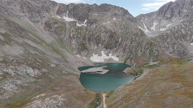 4K Aerial View of a High Mountain Lake Surrounded by Rocky Peaks.