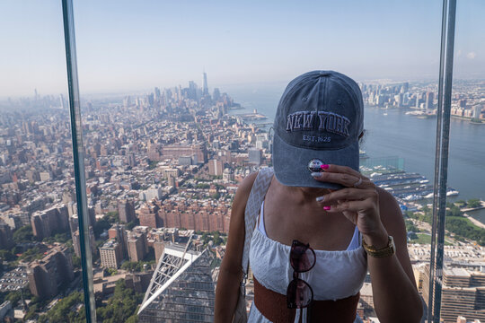 Visitor in a New York cap in front of the skyline of Lower Manhattan on an observation deck, New York, United States